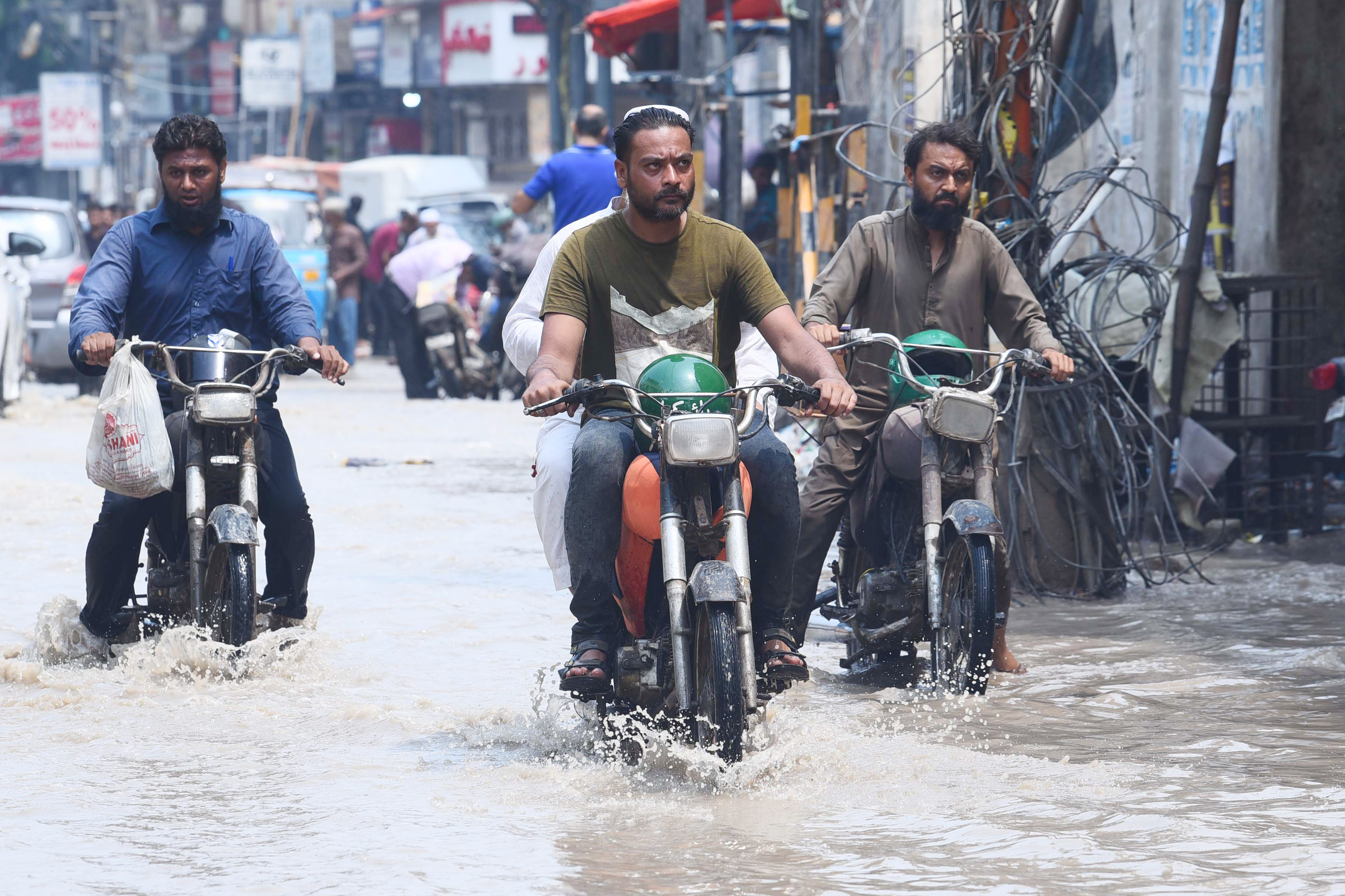 Orang-orang yang mengendarai sepeda motor menerjang jalan yang terendam banjir setelah hujan lebat di kota pelabuhan Karachi, Pakistan selatan, pada 20 Juli 2024. (Xinhua/Str)