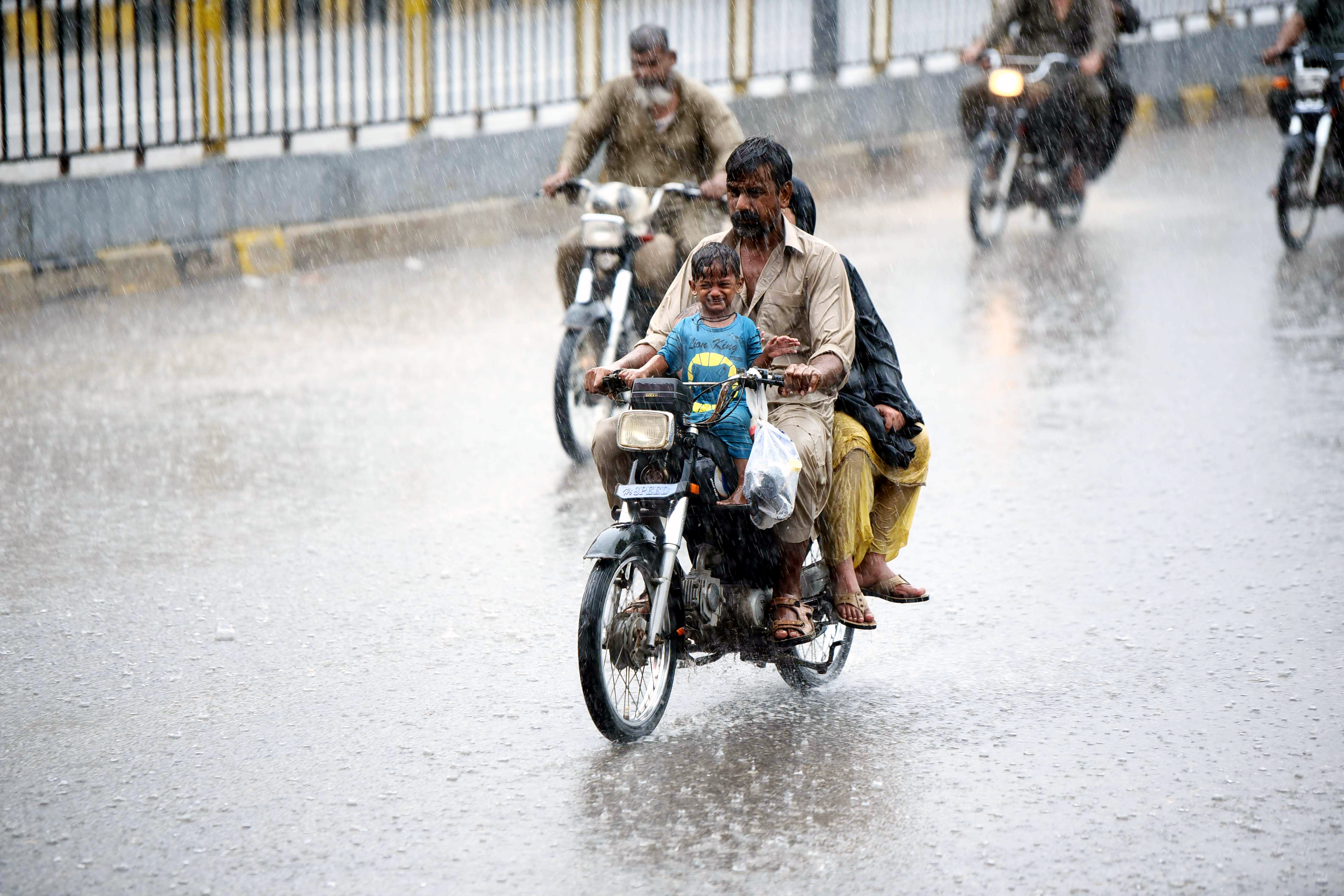 Orang-orang mengendarai sepeda motor di sebuah jalan di tengah hujan lebat di kota pelabuhan Karachi, Pakistan selatan, pada 20 Juli 2024. (Xinhua/Str)